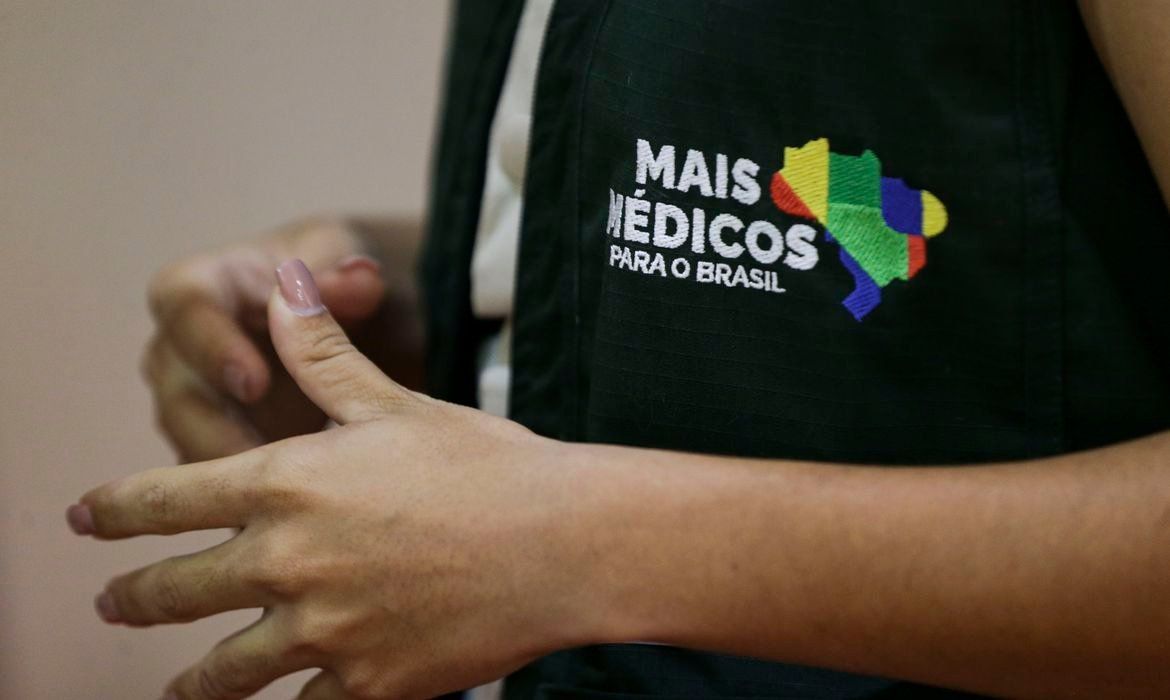 Médico do Programa Mais Médicos em consulta na Atenção Básica, portando seu crachá e documento de Registro Ministério da Saúde (RMS).