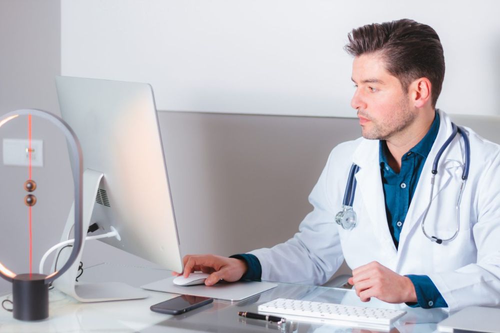 Médico recém-formado analisando um documento jurídico do CFM ao lado de seu carimbo de CRM e estetoscópio na mesa do consultório.