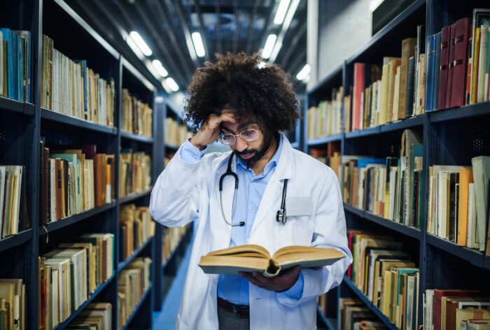Médico em ambiente hospitalar público analisando contratos de trabalho e legislação sobre acumulação de cargos públicos em tablet.