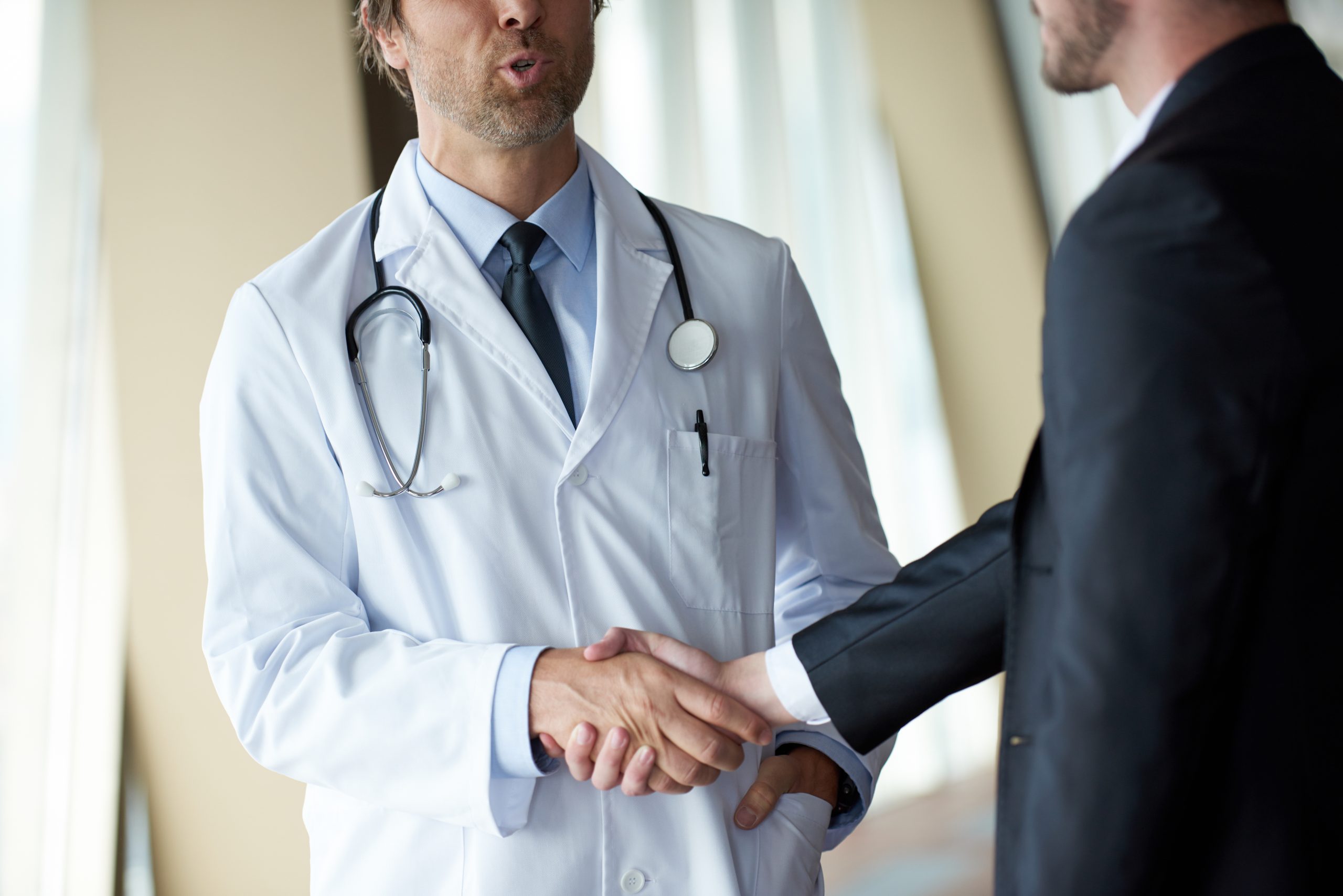 Médico e sócio administrador não médico reunidos em sala corporativa assinando contrato social de clínica médica.